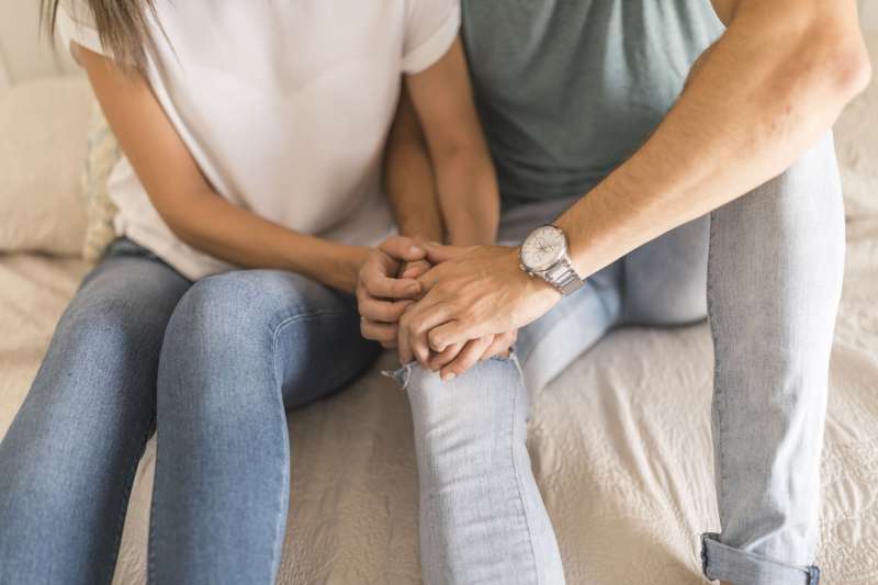 crop-couple-touching-hands-bed